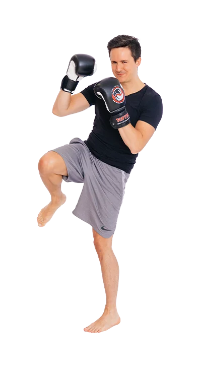 Daniel Mader, MSc (WU) steht in Kampfhaltung mit Boxhandschuhen und hebt das Knie – fokussiert, energiegeladen und sportlich.