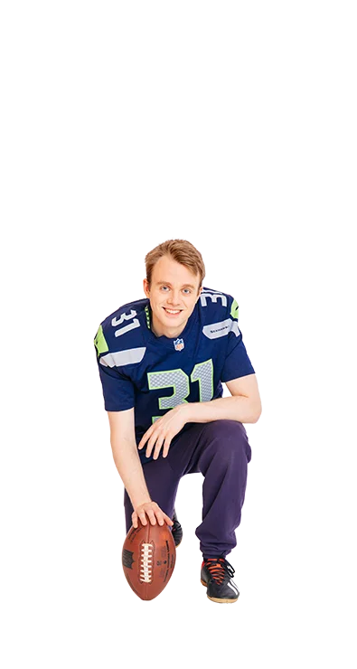 Jan-Michael Bussmann, MSc kniet im American-Football-Outfit mit einem Football in der Hand – sportlich, entschlossen und bereit für den nächsten Spielzug.