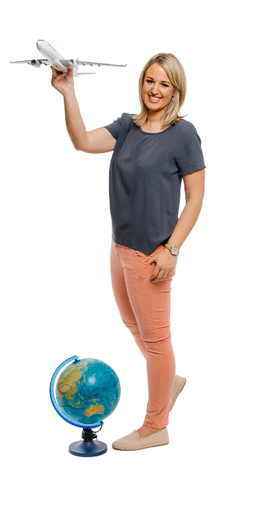 Mag. Katrin Groiss-Schuster hält ein Modellflugzeug in der einen Hand, mit einem Globus zu ihren Füßen – voller Fernweh und Reiselust.