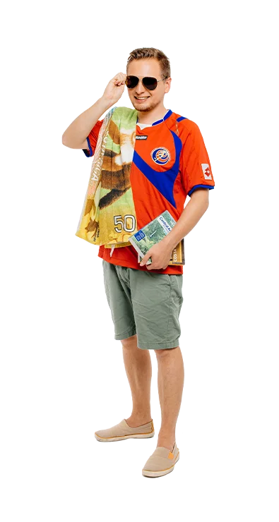 Matthias Obermeier, MSc im Fußballtrikot mit Sonnenbrille und einem Buch in der Hand, dazu ein Costa-Rica-Handtuch – voller Fernweh, Humor und Urlaubsstimmung.