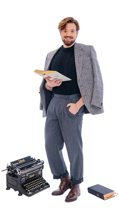 Philipp Zelenka, BSc MSc steht elegant mit Buch in der Hand, neben sich eine alte Schreibmaschine und ein weiteres Buch – stilvoll, belesen und mit einem Hauch Retro-Charme.