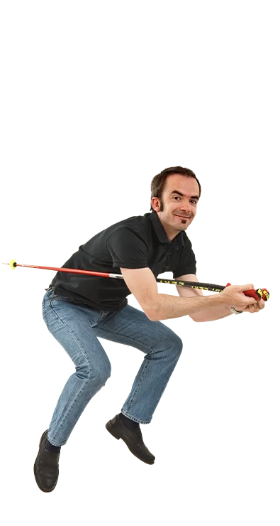 Dr. Stefan Schiel geht tief in die Hocke und hält fokussiert einen Skistock wie ein Slalomfahrer – dynamisch, sportlich und voller Energie.
