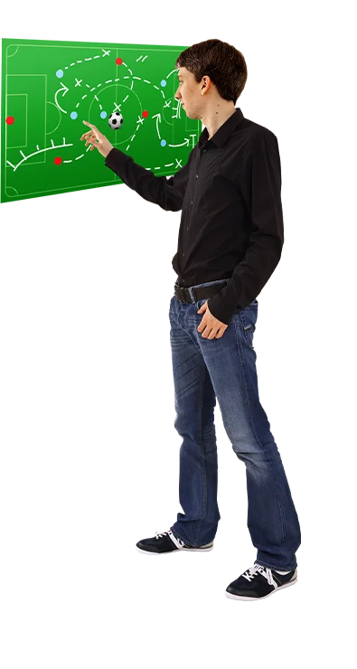 Dipl.-Ing. Thomas Schuster erklärt mit ausgestrecktem Arm eine komplexe Fußballtaktik auf einer Tafel – strategisch, analytisch und mit Leidenschaft für den Sport.
