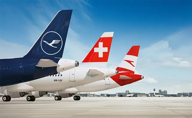 Flugzeuge der verschiedenen Airlines der Lufthansa Gruppe mit sichtbaren Heckflossen auf dem Rollfeld.