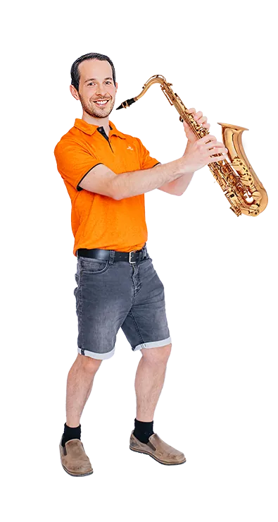 Andreas Kritsch, MSc steht mit einem Saxophon in den Händen und lächelt in die Kamera - musikalisch, humorvoll und voller Spielfreude.