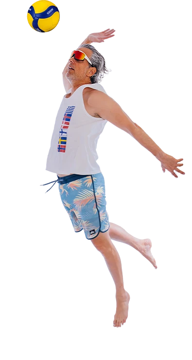 Mag. Erik Stadler springt dynamisch in die Luft und schlägt einen Volleyball über das Netz - sportlich, energiegeladen und voller Sommer-Feeling.
